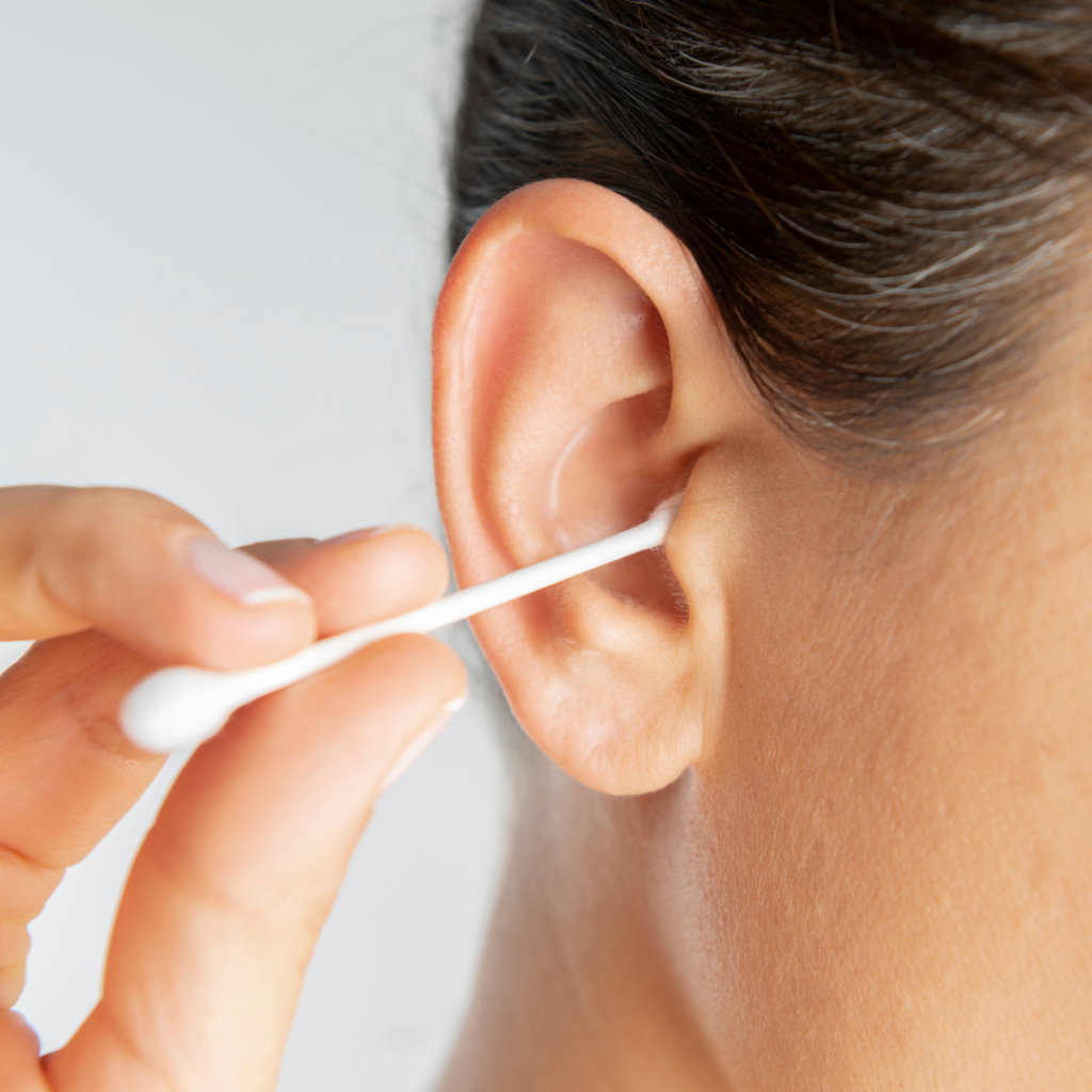 A close-up of a person cleaning their ear with a cotton swab.